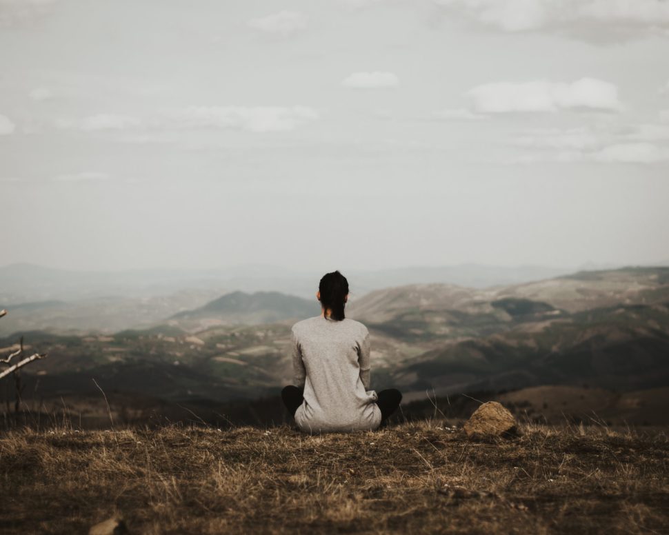 Women sitting on the cliff overlooking mountains